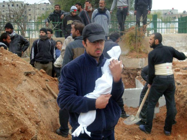egyéves kisfiú teteme egy férfi kezében, aki éhen halt egy damaszkuszi menekült táborban